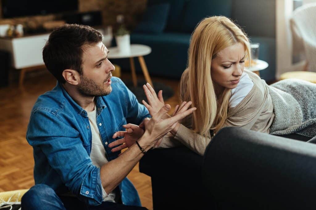 Couple arguing on a couch, highlighting relationship tension and addressing the question Why does my wife yell at me?