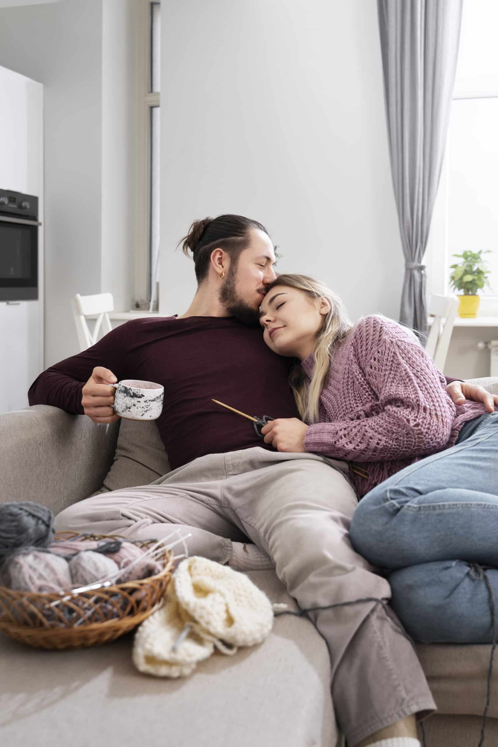 Young couple cuddling on the couch during a knitting session, symbolizing soulmate transformation and deep connection in a busy family life.