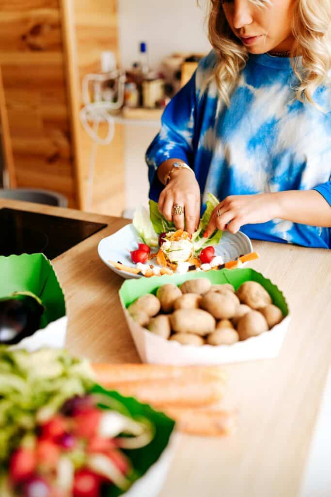 A stay at home mom preparing a fresh and healthy meal in her kitchen, surrounded by vegetables and ingredients.